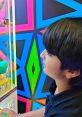 Young child focused on a colorful arcade claw machine, enjoying a fun gaming experience at an entertainment venue.