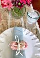 Colorful table setting with decorative flowers, a napkin, and sprinkles-covered donuts for a delightful gathering.