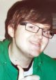 Smiling young man in a green hoodie gives a thumbs up, capturing the cheerful essence of Edd Gould's beloved character.