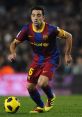 Xavi Hernández dribbling the ball in FC Barcelona kit during a La Liga match, showcasing his midfield prowess.