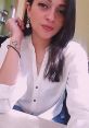 Young woman with long dark hair wearing a white blouse and statement earrings, showcasing a stylish look and confidence.