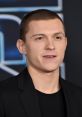 Tom Holland smiles confidently at a premiere event, wearing a black suit and showcasing his signature style.