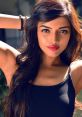 Confident woman with long hair and bold red lips, showcasing her beauty in a stylish tank top against a soft background.