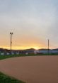 Sunset over a softball field, highlighting Betsy softball's home turf, with bright skies and green grass.