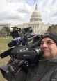 Reporter filming in front of the Capitol Building, capturing significant moments with a professional camera setup.