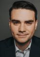 Ben Shapiro confidently smiles, showcasing his intellectual charisma and distinctive style in a professional portrait.