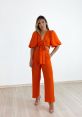 Stylish woman in trendy orange outfit with tie detail, showcasing vibrant fashion inspired by Laranja Betânia.