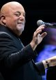 Billy Joel performing live, engaging with fans from the stage, showcasing his iconic music talent and charisma.