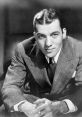 Classic black and white portrait of Ed Sullivan in a tailored suit, showcasing his charismatic smile and stylish hairstyle.