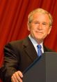 George W. Bush smiles at a podium, showcasing his leadership as the 43rd U.S. President, against a red backdrop.