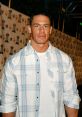 John Cena in a casual plaid shirt, showcasing his signature style at a public event with a lively background.