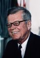 John F. Kennedy smiling while wearing glasses, showcasing his charisma as the 35th U.S. President during a pivotal era.