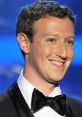 Mark Zuckerberg smiling at a formal event, wearing a black tuxedo with a bow tie against a blue background.