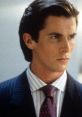 Patrick Bateman, dressed in a sharp suit and red tie, exudes confidence and a chilling demeanor in a corporate setting.