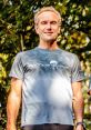 Smiling man in a Running Wolf shirt stands outdoors, showcasing active lifestyle and community engagement in nature.