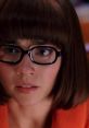 Velma Dinkley, portrayed by Linda Cardellini, showcases her signature glasses and thoughtful expression in a colorful setting.