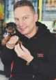 Giovanny Rivera holding a small Yorkie puppy, showcasing their joyful bond in a vibrant setting.