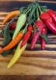 Colorful assortment of fresh chili peppers on a wooden surface, highlighting vibrant colors and textures ideal for recipes.