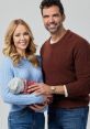 Happy family portrait of Braden Blair and partner with their newborn, showcasing love and togetherness in cozy sweaters.