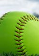 Bright green BQB softball with red stitching resting on grass, perfect for vibrant gameplay and outdoor sports activities.