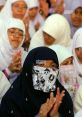 Young women in hijabs and masks clapping at an event, showcasing cultural attire and community support.