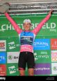 Hannah Barnes celebrating on the podium, showcasing her victory in a colorful cycling kit at a cycling event.