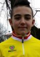 Young athlete Gianni Cavallini smiles in a vibrant yellow cycling jersey, outdoors with trees in the background.