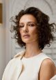 Elegant woman with curly hair, showcasing a sophisticated style and confident expression, embodying modern beauty trends.