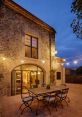 Cozy stone terrace of MASIA4, illuminated at dusk, featuring a dining table and inviting outdoor ambiance. Perfect for gatherings.