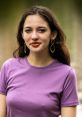 Kirsten Calica wearing a purple shirt and stylish earrings, posing outdoors with a natural backdrop.