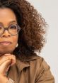 Oprah Winfrey with curly hair, glasses, and thoughtful expression, showcasing her inspirational persona.