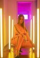 Young woman in vibrant pink tracksuit posing confidently amidst neon lights, showcasing a stylish and modern aesthetic.