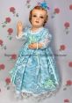 Vintage doll dressed in blue lace, adorned with flowers, perfect for collectors and enthusiasts of Jaqui Gonzalez designs.