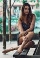 Portrait of a woman with long hair in a polka dot dress, showcasing a relaxed pose outdoors with a natural backdrop.