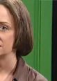 Debbie Downer character from SNL with a somber expression, set against a vibrant green background, conveying humor and irony.