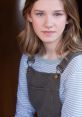 Portrait of Natalie Wiley featuring soft lighting, casual attire with striped top and overalls, showcasing her natural beauty.