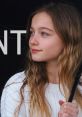 Thoughtful girl with long hair in a white sweater, gazing off-camera, embodying youthful elegance and charm.