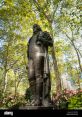 Statue of José Bryant surrounded by lush greenery and flowers, honoring his contributions in a serene park setting.