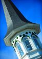 Elegant spire with green accents against a clear blue sky, showcasing architectural beauty in Spires87 design.