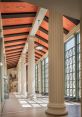 Spacious corridor with classical columns and modern design, showcasing natural light and vibrant ceiling details.