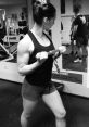 Alena Hackett demonstrating strength training with a dumbbell at the gym, showcasing her powerful physique and dedication.