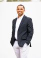 Professional portrait of Isaiah Denman, wearing a blazer and smiling confidently against a neutral background.