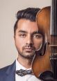 Ranjodh Bajwa striking a pose with a violin, showcasing his musical talent and artistic style in a sophisticated portrait.