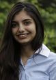 Smiling portrait of Anjali Sehduera in a light blue shirt, set against a blurred green background.