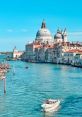 Scenic view of Venice with historic buildings, stunning domes, and boats gliding through the shimmering blue canal waters.