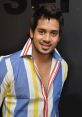 Bharath smiling in a colorful striped shirt, showcasing his stylish look against a dark background.