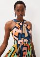 Stylish woman in a colorful geometric dress with a belted waist, showcasing modern fashion and vibrant patterns.