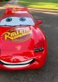 Red Lightning McQueen car with Rust-eze branding, featuring big eyes and a cheerful smile, on a tree-lined road.