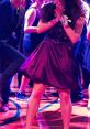 Woman in a purple dress dancing joyfully at a vibrant party, celebrating with friends in a festive atmosphere.