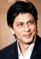 Shahrukh Khan smiling, showcasing his iconic charm and charisma, dressed in formal attire at a public event.